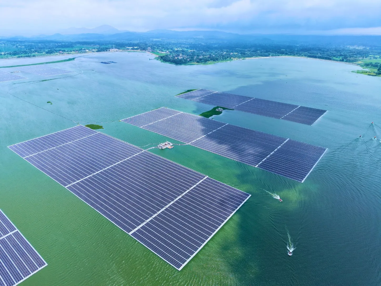 Aerial view of a utility-scale floating solar plant on a reservoir divided into separate array blocks with service boats between them
